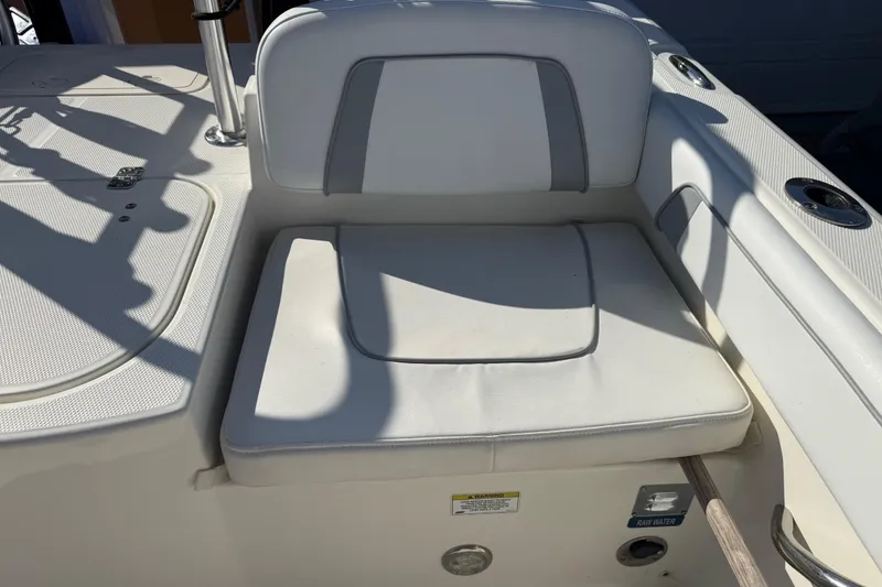 Slide: The Image of 2014 Carolina Cat 23DC boat seat with white cushioned upholstery and cup holders. - 23