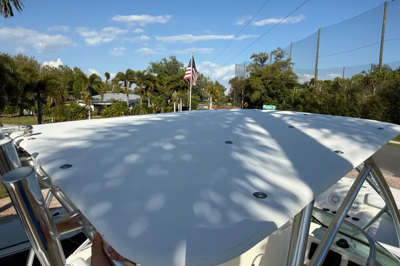 Slide: The Image of 2014 Carolina Cat 23DC boat with T-top, surrounded by trees and clear sky. - 52