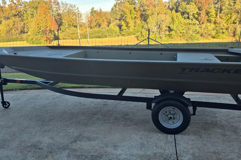 The Image of 2026 Tracker Grizzly 1648 Utility boat on trailer, parked outdoors with autumn trees in background. - 0