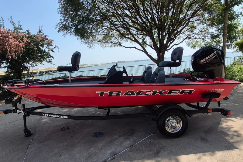 The Image of 2026 Tracker Pro Team 175 boat on trailer by lakeside, featuring vibrant red design. - 0