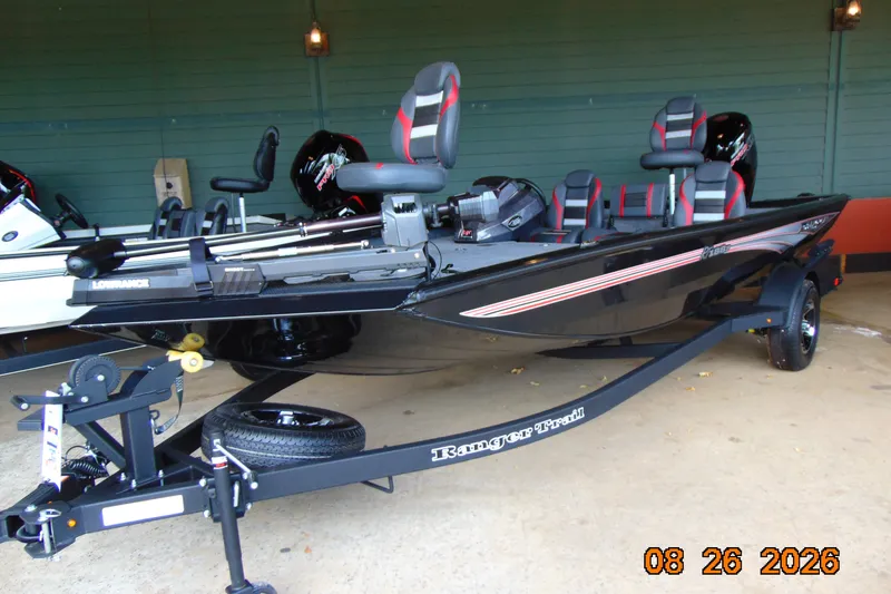 The Image of 2026 Ranger RT188P fishing boat on trailer, black with red accents, parked indoors. - 0