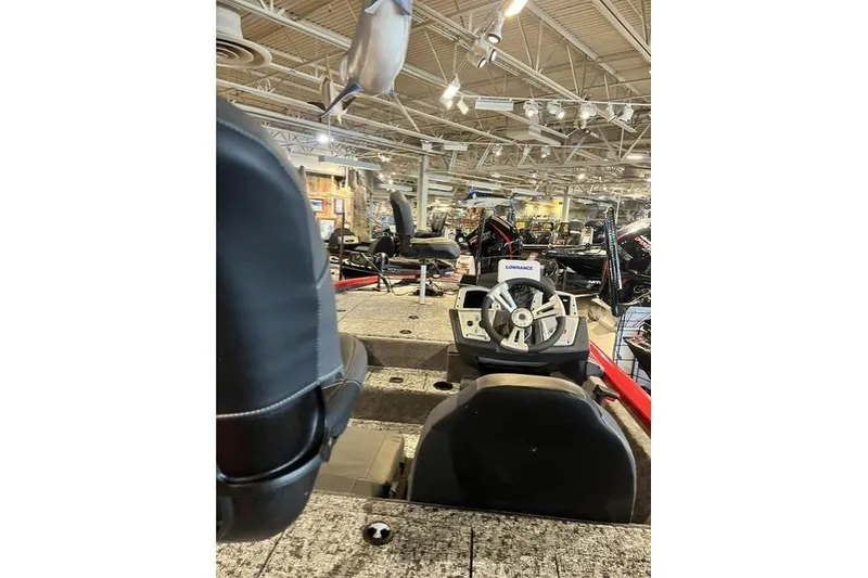 Slide: The Image of 2026 Tracker Pro Team 195 boat interior with steering wheel and seating in showroom. - 2