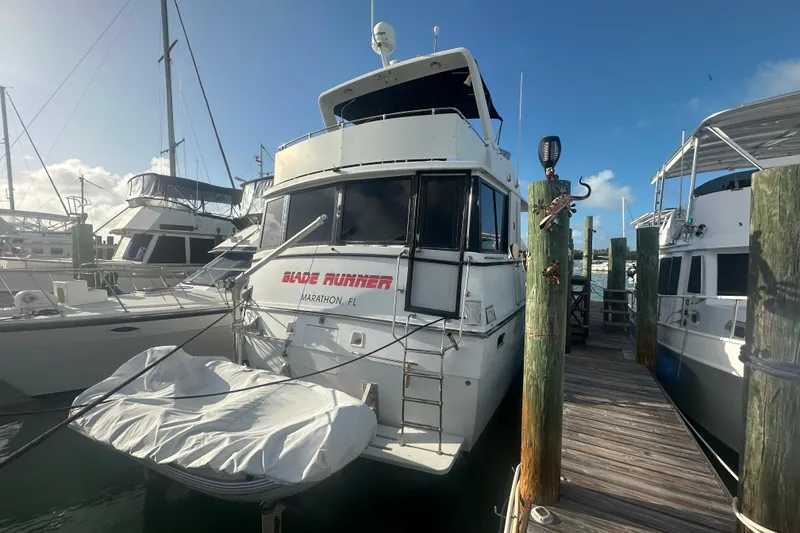The Image of 1988 Chris Craft 46 Constellation yacht docked, featuring "Blade Runner" name and covered dinghy. - 1