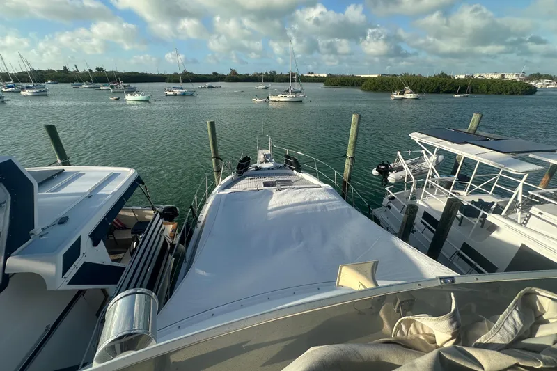 Slide: The Image of 1988 Chris Craft 46 Constellation yacht docked in a scenic marina with sailboats. - 11