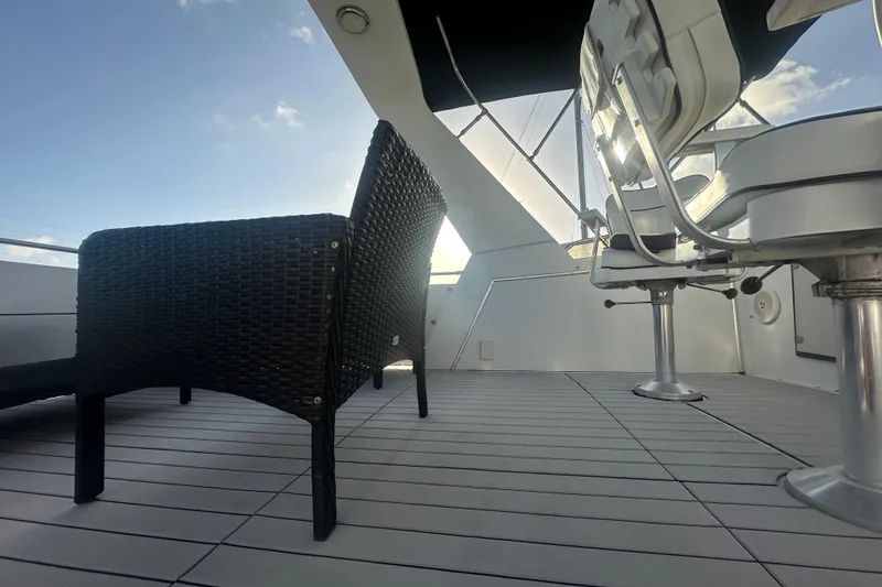 Slide: The Image of 1988 Chris Craft 46 Constellation yacht deck with wicker and swivel chairs under a clear sky. - 17