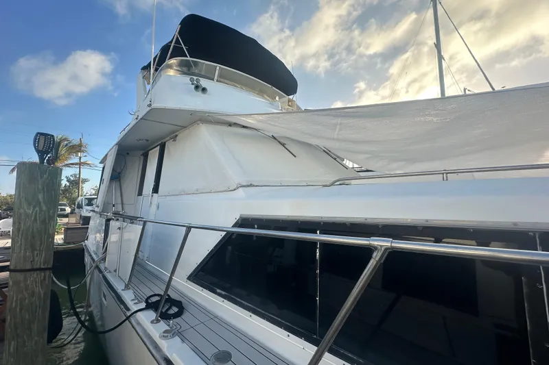 Slide: The Image of 1988 Chris Craft 46 Constellation yacht docked under a partly cloudy sky. - 8
