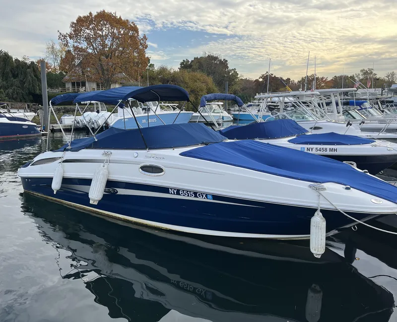 Slide: The Image of 2011 Sea Ray 260 Sundeck boat docked in marina, blue and white design, covered with canopy. - 1