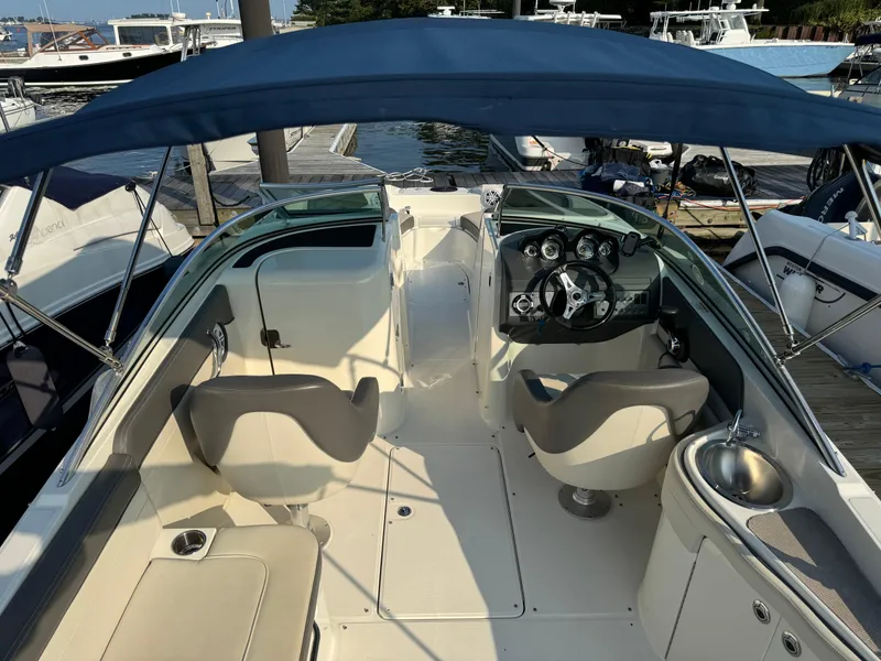 Slide: The Image of 2011 Sea Ray 260 Sundeck boat interior with seating and steering wheel, docked at marina. - 10