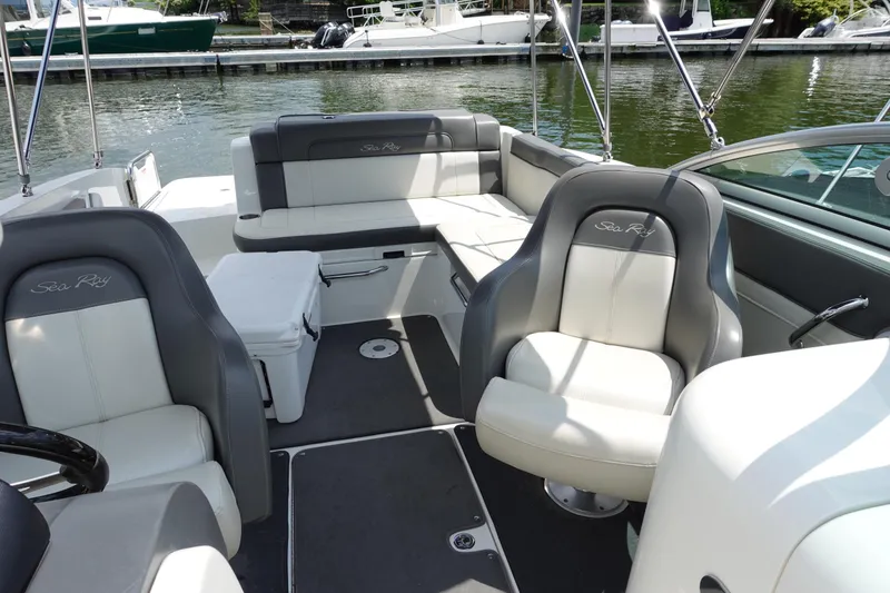 Slide: The Image of 2011 Sea Ray 260 Sundeck interior with gray and white seating, docked by the water. - 9