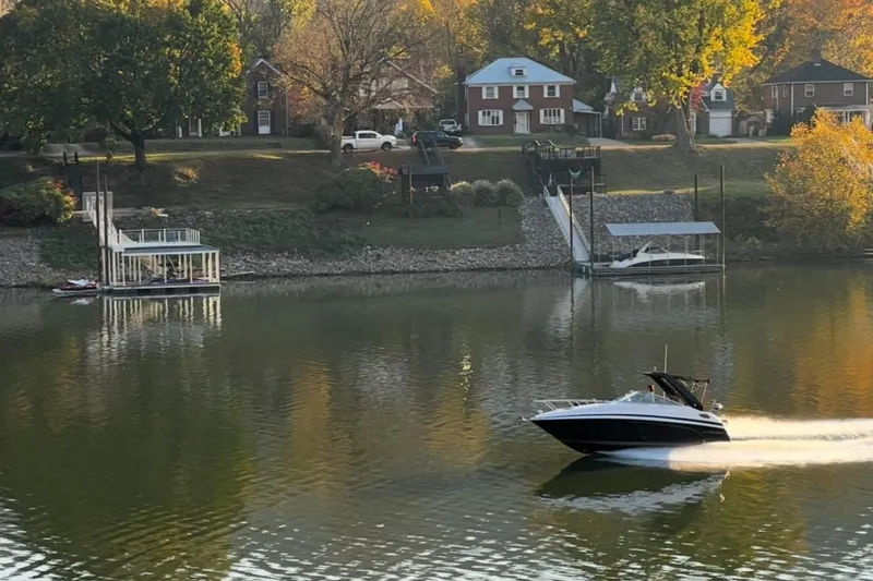Slide: The Image of 2015 Regal 28 Express boat cruising on a calm river near waterfront homes. - 3