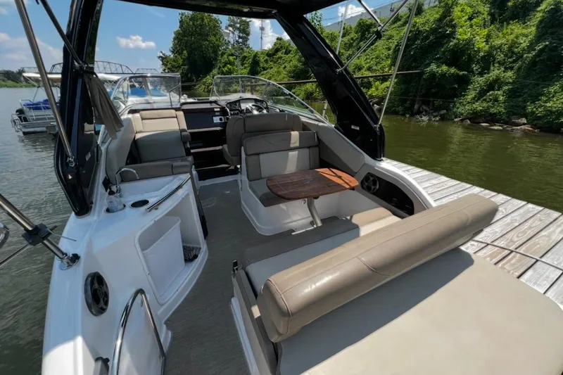 Slide: The Image of 2015 Regal 28 Express boat interior with seating and table, docked by lush greenery. - 6