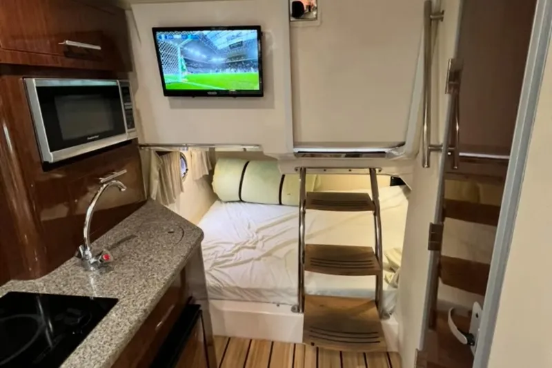 Slide: The Image of 2015 Regal 28 Express cabin interior with kitchenette, bed, and mounted TV. - 7