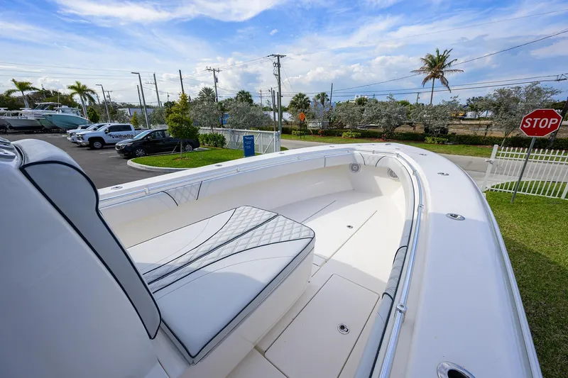 Slide: The Image of 2019 Contender 35 ST boat with sleek seating, parked near a road with palm trees. - 19