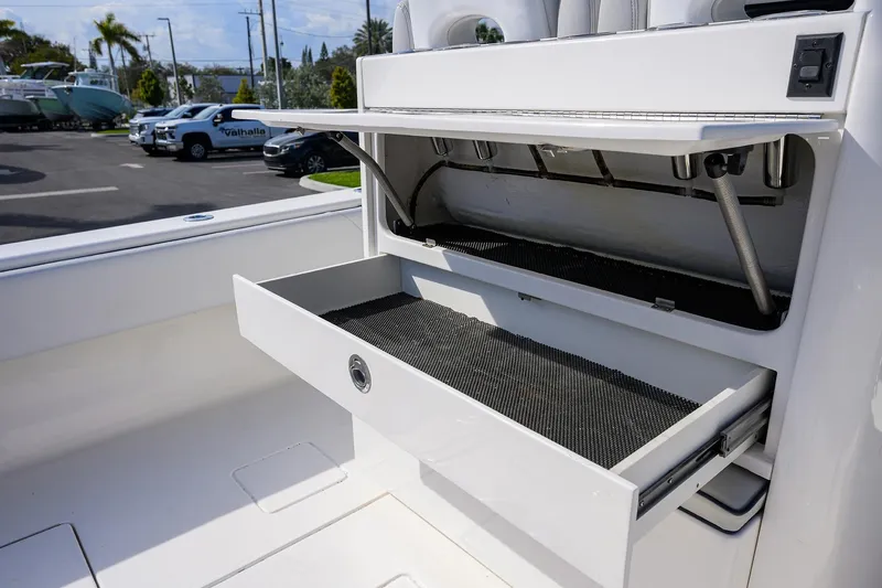 Slide: The Image of 2019 Contender 35 ST boat storage compartment with open drawers in a marina setting. - 27