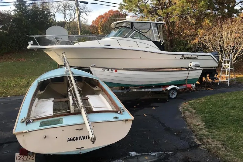 The Image of Two boats on trailers: 2002 Pursuit 3070 Express and a small sailboat named "Aggrivation." - 0