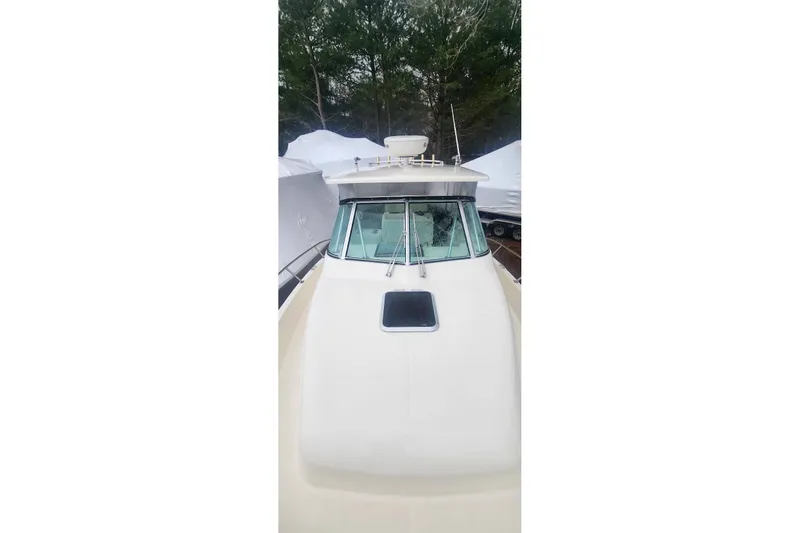 Slide: The Image of Bow view of a 2003 Pursuit 3070 Express boat, docked with covered vessels nearby. - 15