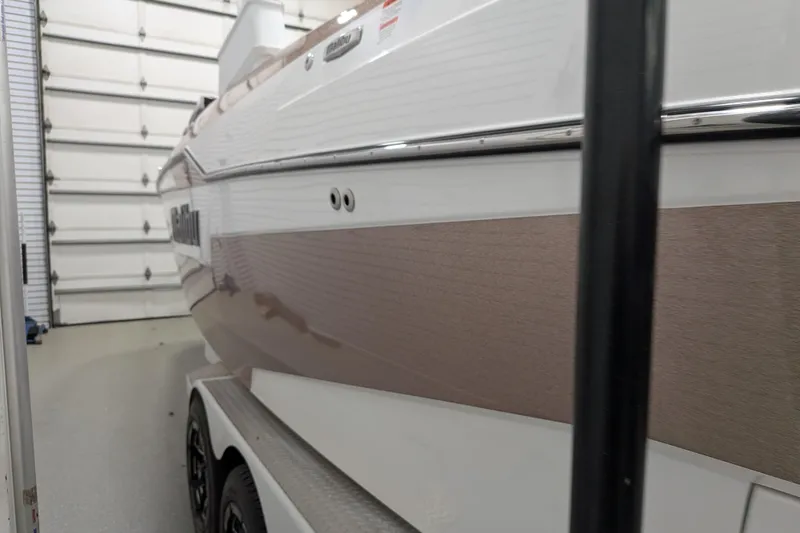 Slide: The Image of 2021 Malibu M240 boat in garage, side view with trailer. - 12