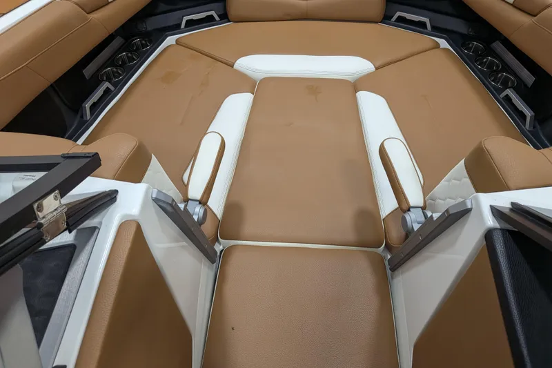 Slide: The Image of 2021 Malibu M240 boat interior with tan and white seating, cup holders visible. - 16