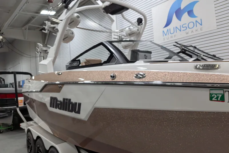 Slide: The Image of 2021 Malibu M240 boat in showroom, featuring sleek design and Munson Surf Wake branding. - 2