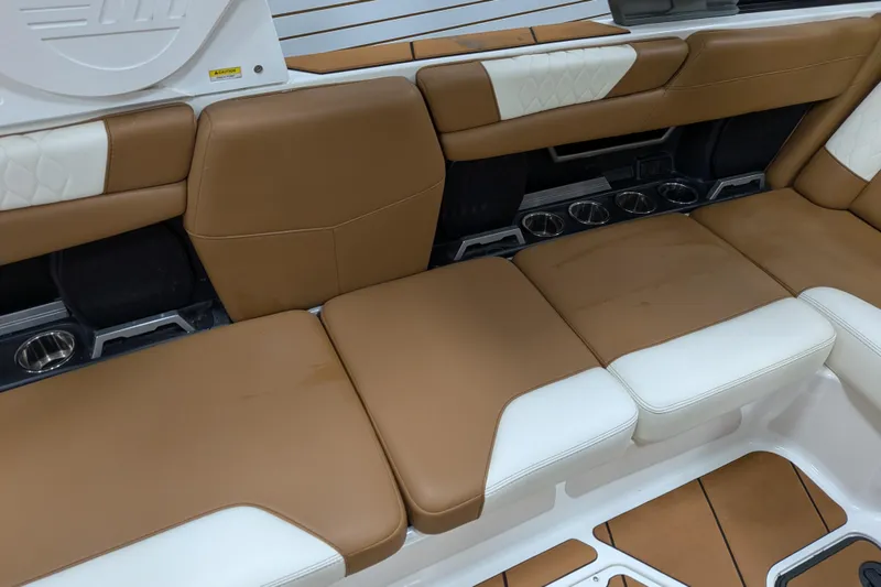 Slide: The Image of 2021 Malibu M240 boat interior with tan and white cushioned seating. - 23