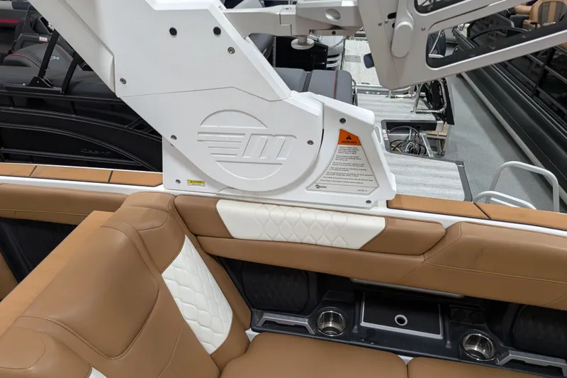 Slide: The Image of 2021 Malibu M240 boat interior with tan and white seating, featuring cup holders and sleek design. - 29