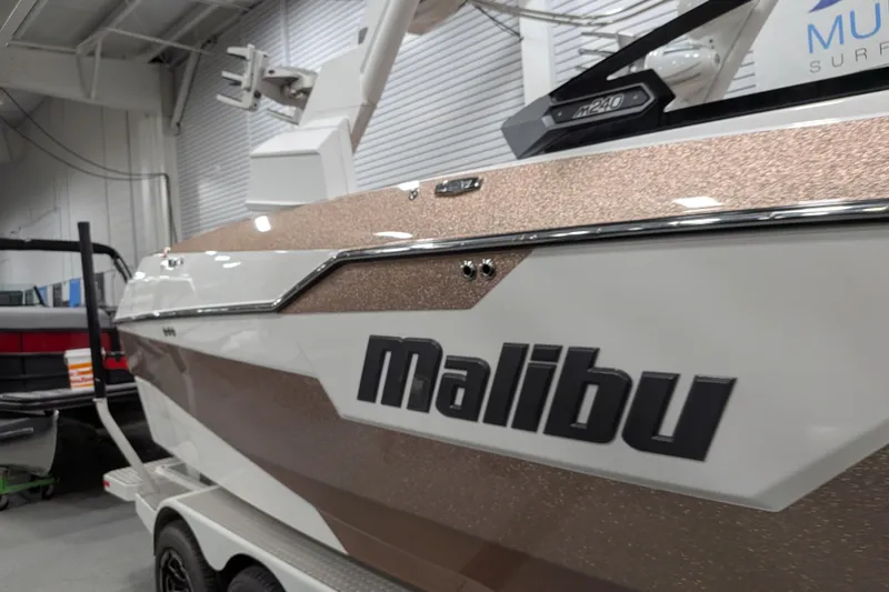 Slide: The Image of 2021 Malibu M240 boat in showroom, featuring sleek design and metallic accents. - 5
