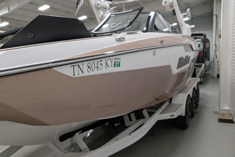 Slide: The Image of 2021 Malibu M240 boat in showroom, side view with registration number visible. - 7