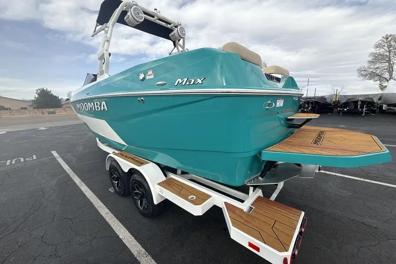 Slide: The Image of 2026 Moomba Max boat in teal, parked on a trailer in a lot. - 3