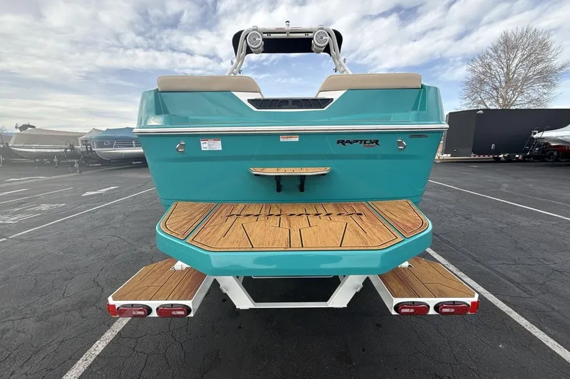 Slide: The Image of 2026 Moomba Max boat with teal exterior and wooden deck in parking lot. - 4