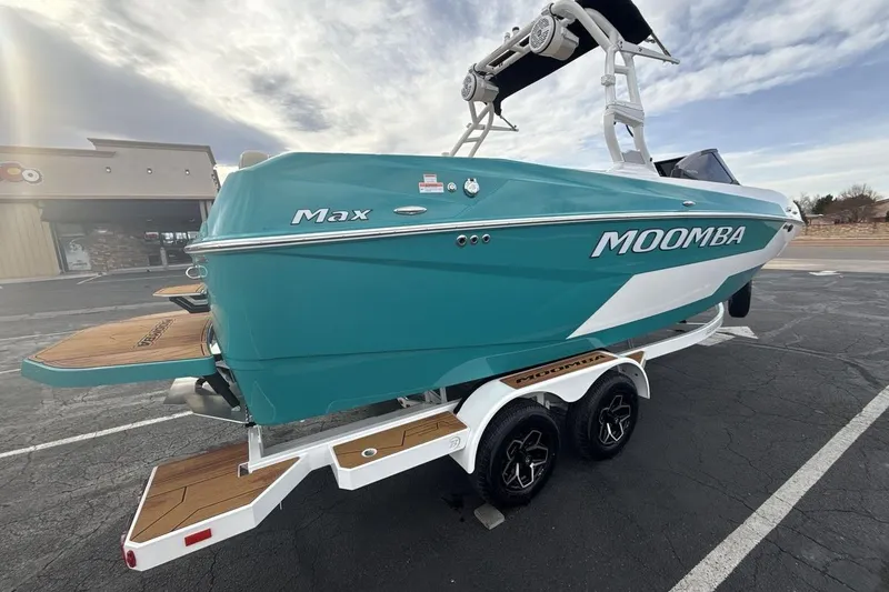 Slide: The Image of 2026 Moomba Max boat on trailer, teal color, parked in lot under cloudy sky. - 5