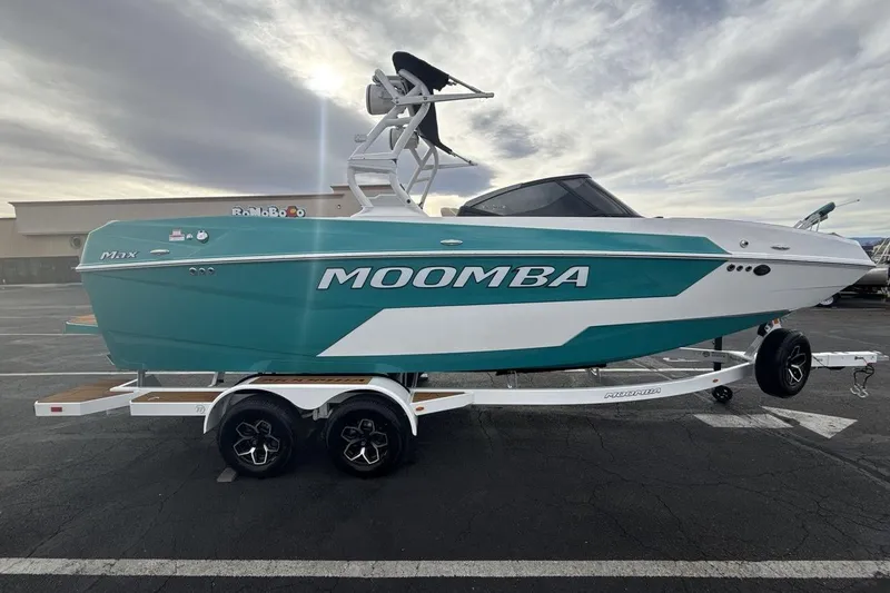 Slide: The Image of 2026 Moomba Max boat in teal and white on a trailer in a parking lot. - 6