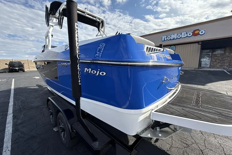 Slide: The Image of 2025 Moomba Mojo boat in vibrant blue, parked outside a building under a clear sky. - 3