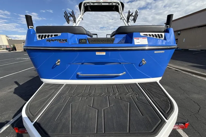 Slide: The Image of 2025 Moomba Mojo boat, blue exterior, Raptor engine, parked on asphalt. - 4