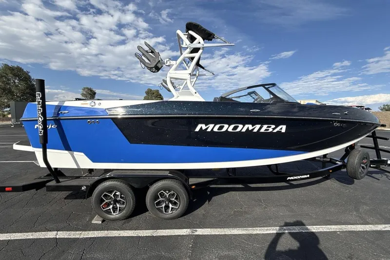 Slide: The Image of 2025 Moomba Mojo boat in blue and black on a trailer under a clear sky. - 6