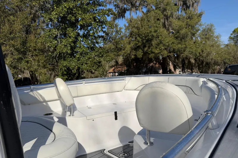 Slide: The Image of 2020 Sportsman Open 212 Center Console boat interior with white seating and lush greenery background. - 12