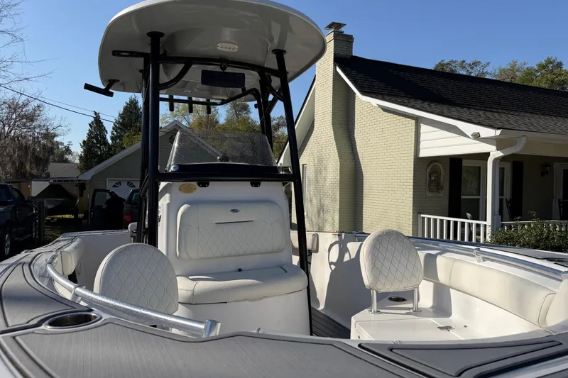 Slide: The Image of 2020 Sportsman Open 212 Center Console boat with white seating, parked near a house. - 13