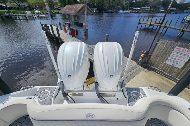 Slide: The Image of 2025 Sea Hunt Ultra 275 SE boat with dual engines docked by a serene waterfront. - 10