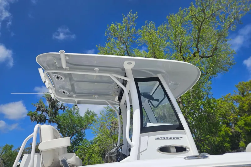 Slide: The Image of 2025 Sea Hunt Ultra 275 SE boat with T-top against blue sky and trees. - 4