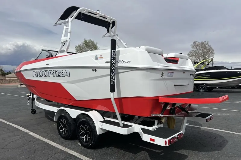 Slide: The Image of 2025 Moomba Max boat in red and white on a trailer, parked outdoors. - 3