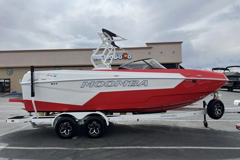Slide: The Image of 2025 Moomba Max boat in red and white on a trailer, parked outdoors. - 6