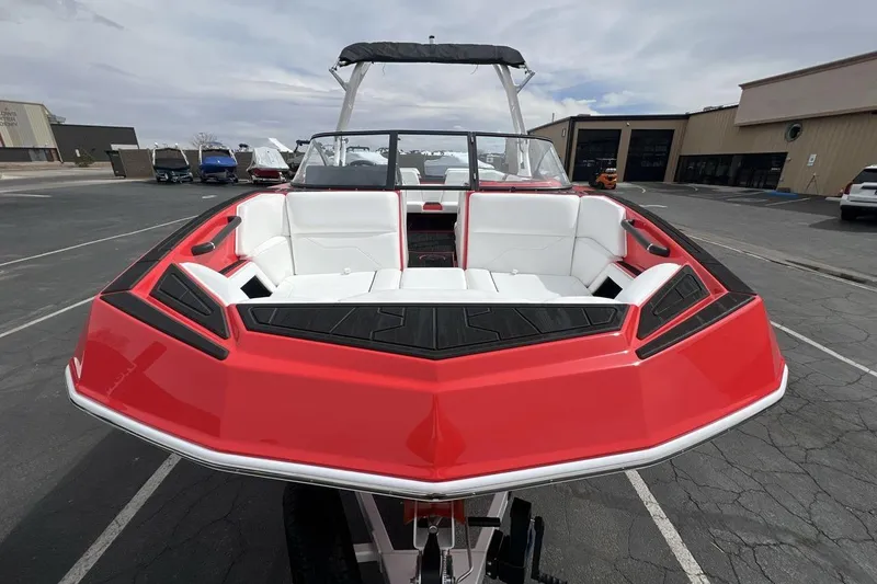 Slide: The Image of 2025 Moomba Max boat with red exterior and white seating, parked outdoors. - 8