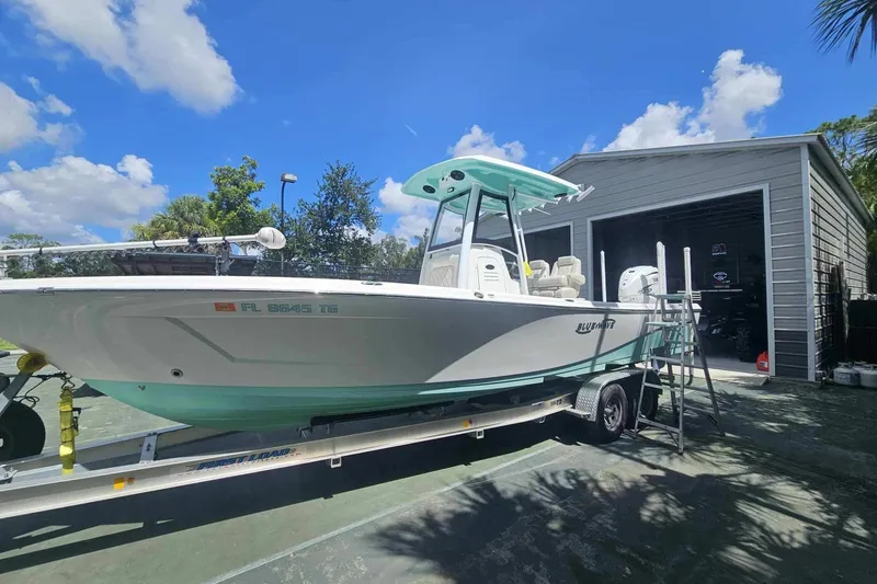 The Image of 2022 Blue Wave 2800 Pure Hybrid boat on trailer, parked near a garage under a clear sky. - 0