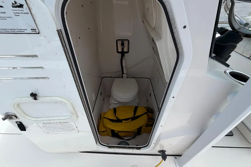 Slide: The Image of Interior of 2022 Blue Wave 2800 Pure Hybrid boat showing a compact marine toilet. - 13