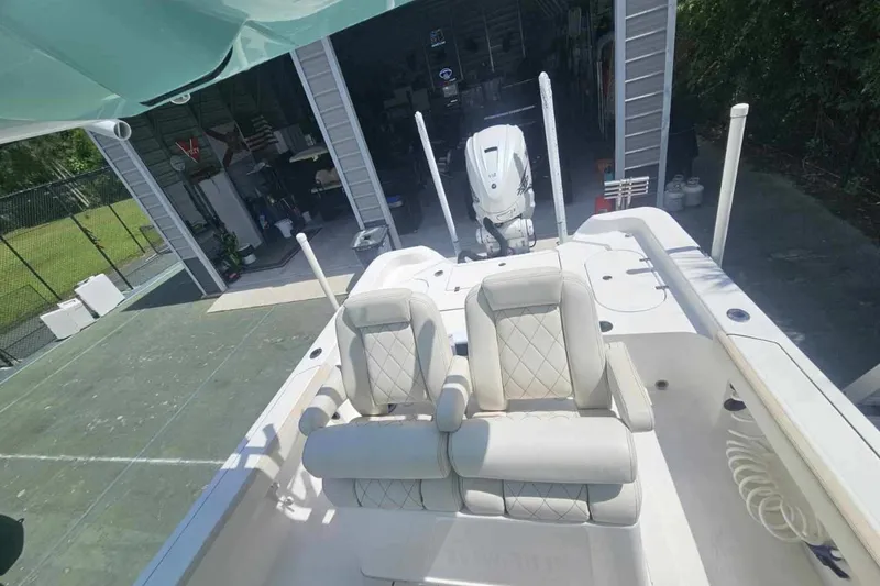 Slide: The Image of 2022 Blue Wave 2800 Pure Hybrid boat with dual seats and outboard motor in a garage. - 2