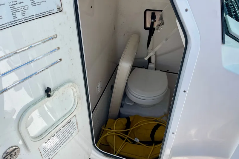 Slide: The Image of Interior of 2022 Blue Wave 2800 Pure Hybrid boat showing a compact marine toilet. - 27