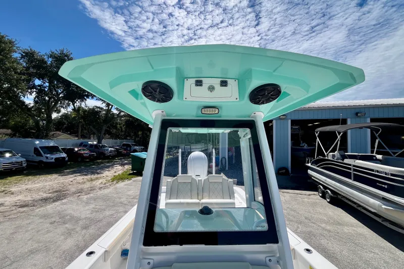 Slide: The Image of 2022 Blue Wave 2800 Pure Hybrid boat with teal canopy, parked outdoors under a blue sky. - 26