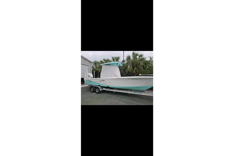 Slide: The Image of 2022 Blue Wave 2800 Pure Hybrid boat on trailer, parked near palm trees. - 6