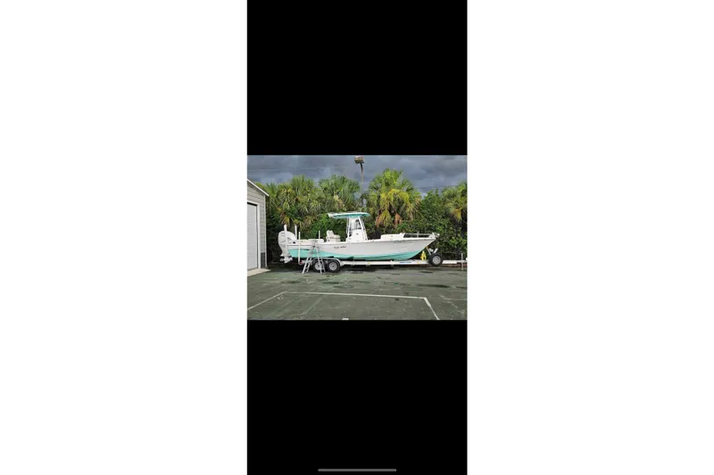 Slide: The Image of 2022 Blue Wave 2800 Pure Hybrid boat on trailer, parked near tropical foliage. - 7