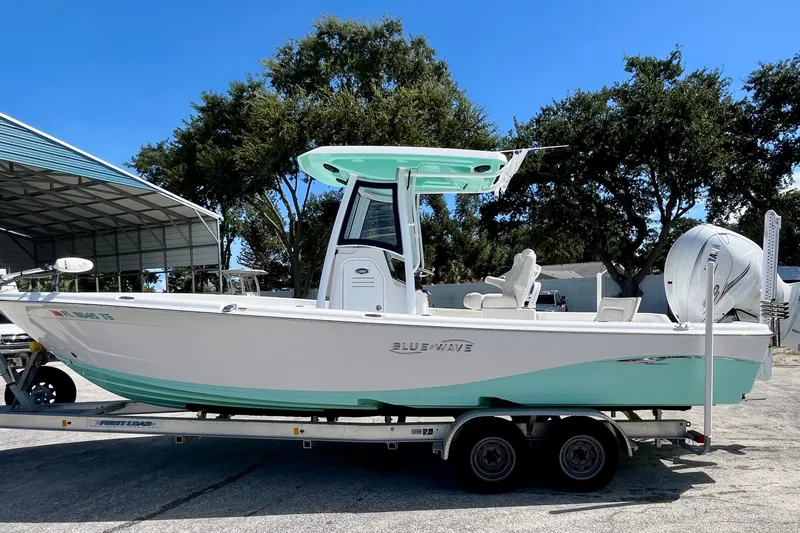 Slide: The Image of 2022 Blue Wave 2800 Pure Hybrid boat on trailer, parked outdoors under clear sky. - 1