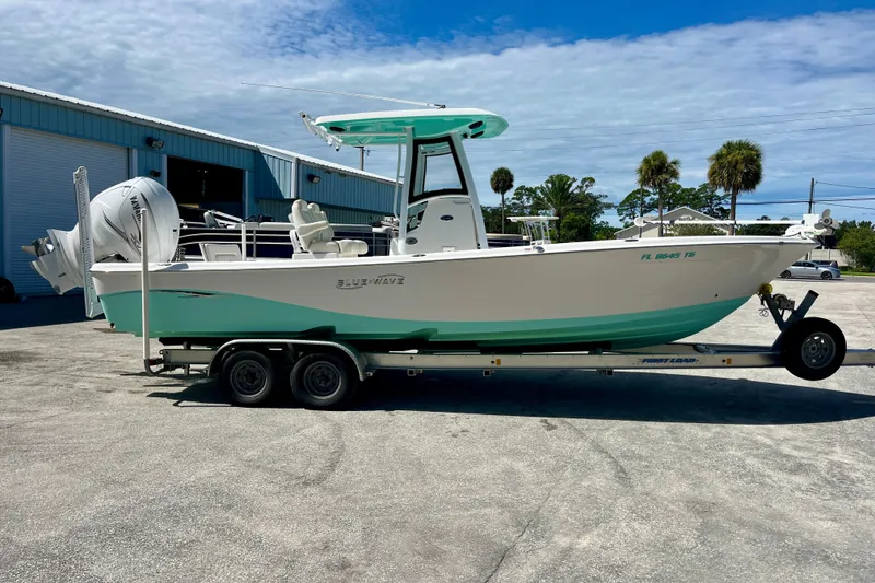Slide: The Image of 2022 Blue Wave 2800 Pure Hybrid boat on trailer, parked outdoors under blue sky. - 5